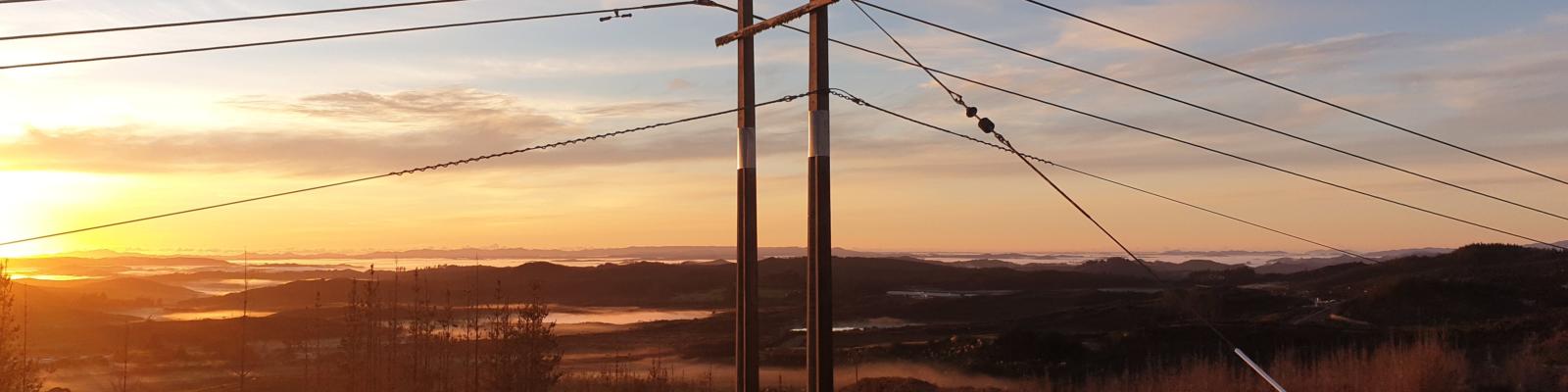 Powerlines in front of Ngawha landscape at sunset. 
